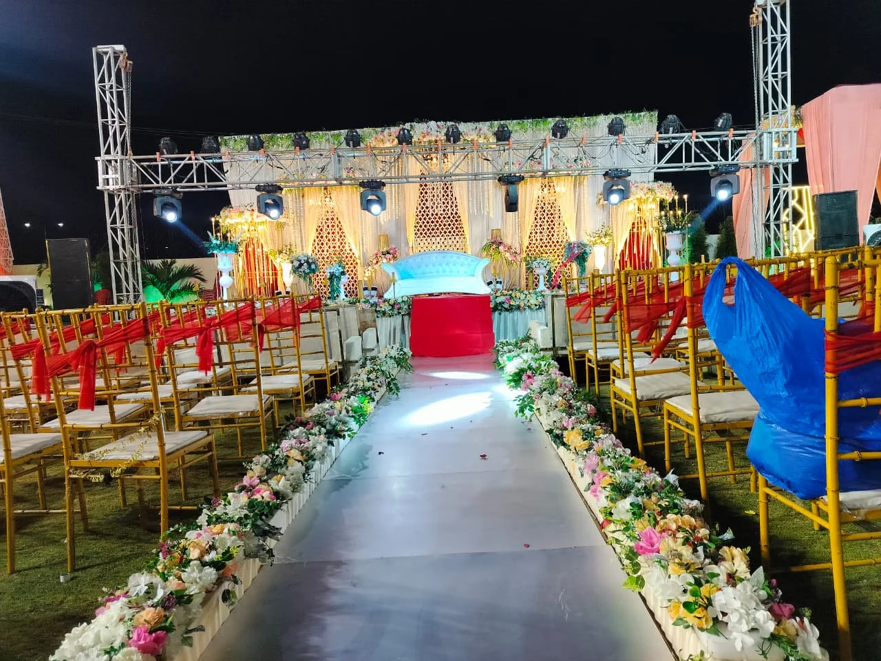 Outdoor wedding aisle lined with flowers and gold chairs
